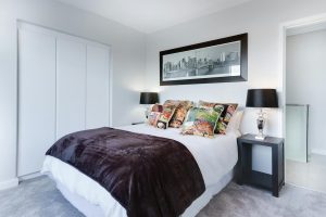 Stylish and contemporary bedroom featuring a cityscape artwork, colorful pillows, and modern decor.