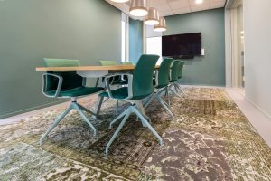 Stylish conference room with green chairs and patterned carpet, perfect for meetings.