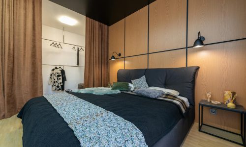 Contemporary bedroom with cozy bedding and stylish wooden paneling.