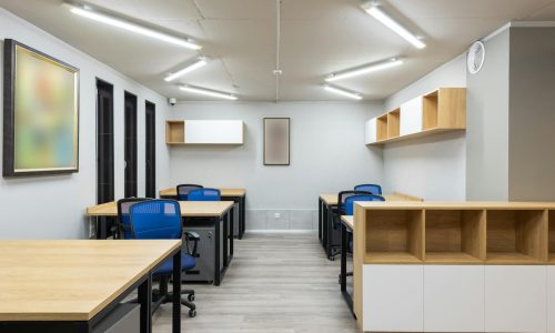 Interior of contemporary workspace with office chairs at tables and wooden shelves under ceiling with geometric lamps