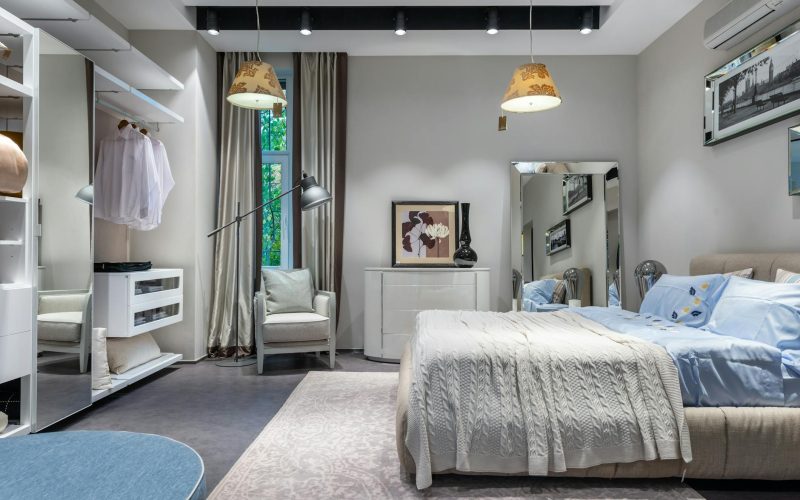 Comfortable bedroom with knitted coverlet and cushions built in spacious wardrobe armchair chest and mirror and hanging lamps