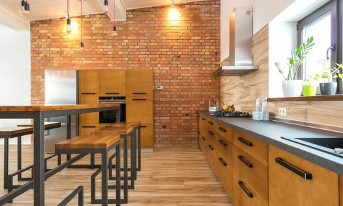 Contemporary kitchen featuring brick wall, wooden cabinets, and sleek design elements with ample natural light.